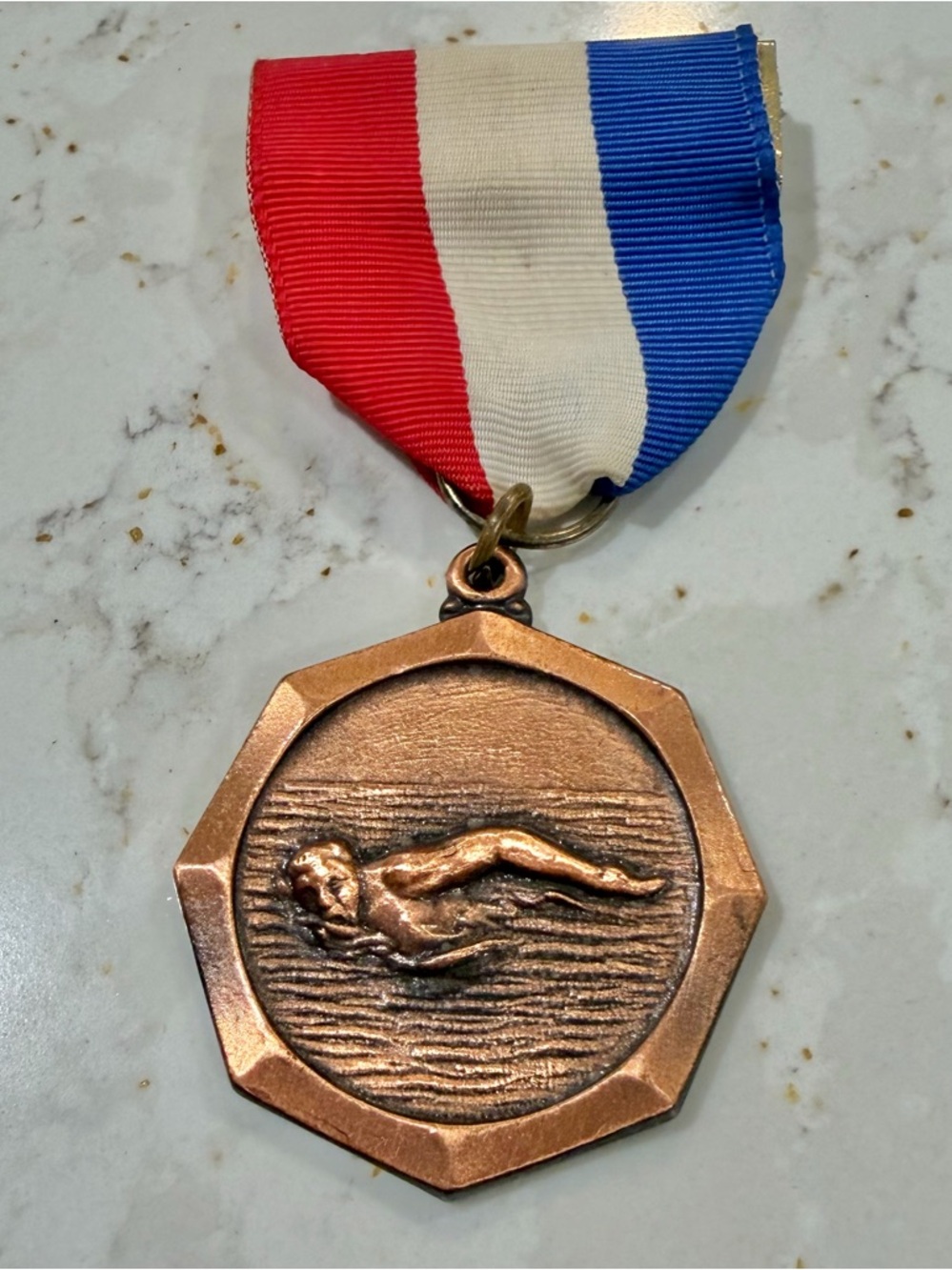 Bronze swimming medal with red, white, and blue ribbon